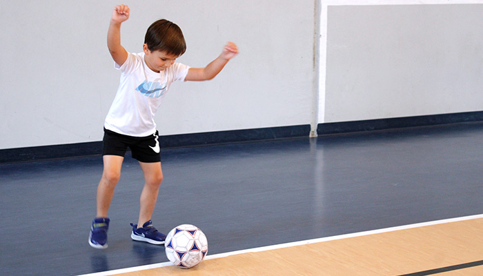 boy kicking soccer ball in gym