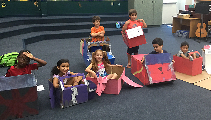 students in cardboard cars