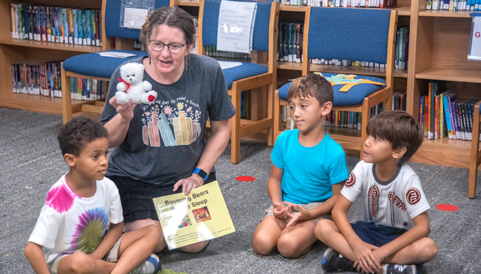 3 boys reading story with librarian