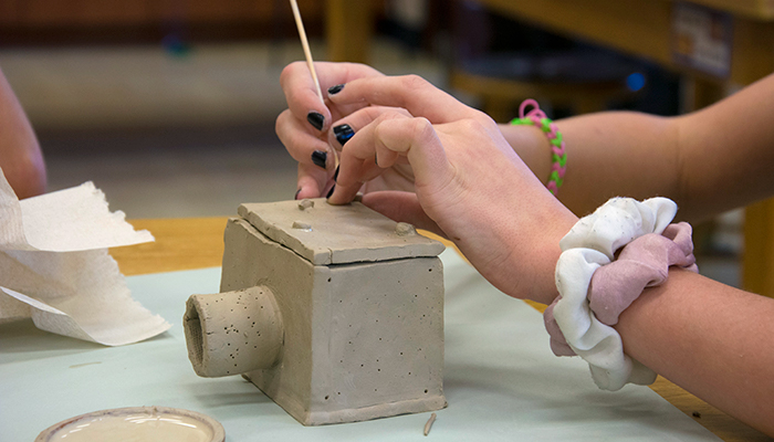 girl working with clay to make sculpture
